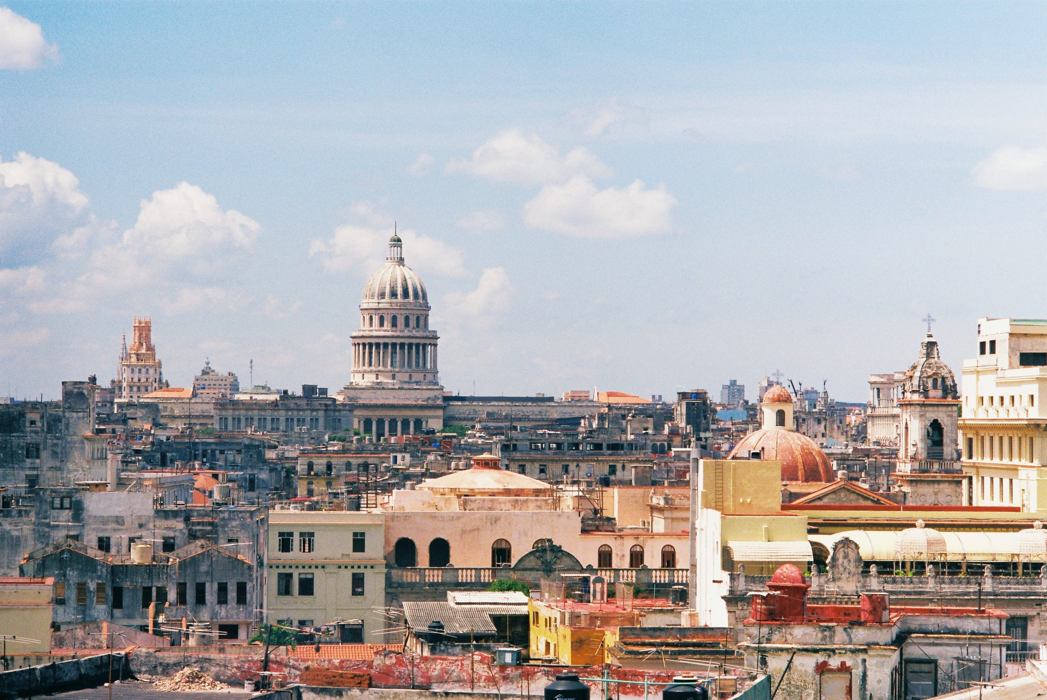 Havana rooftop panorama with El Capitolio silver dome, red church dome, and colonial buildings stretching to the horizon, Cuba