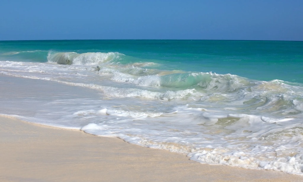Turquoise waves rolling onto white sand Cuba beach