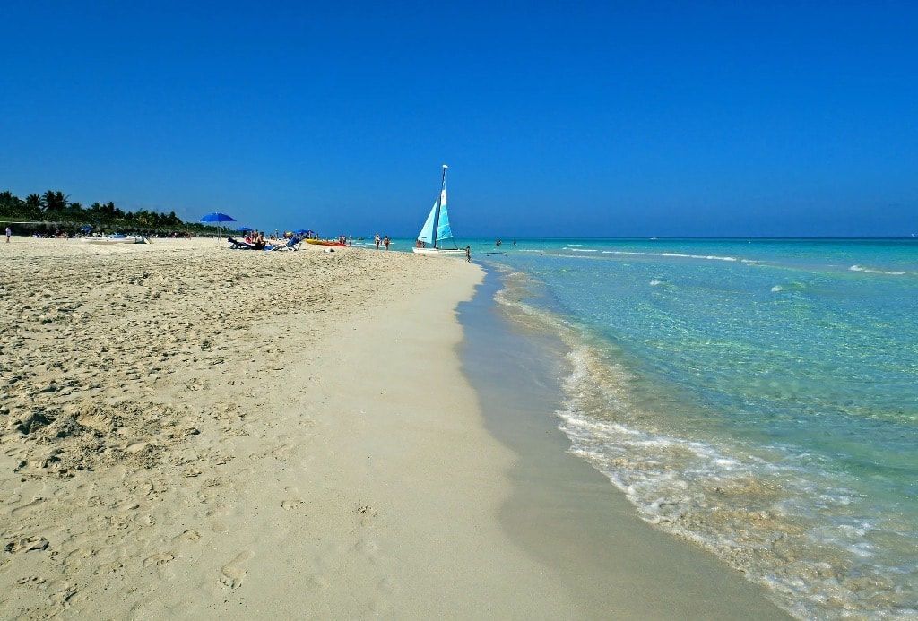 Cuba beach with blue sailboat and crystal clear water