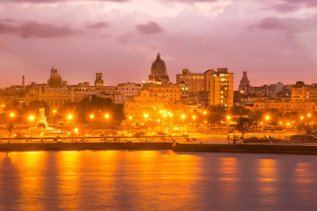 Havana Capitol dome and Malecón waterfront illuminated at dusk purple sky