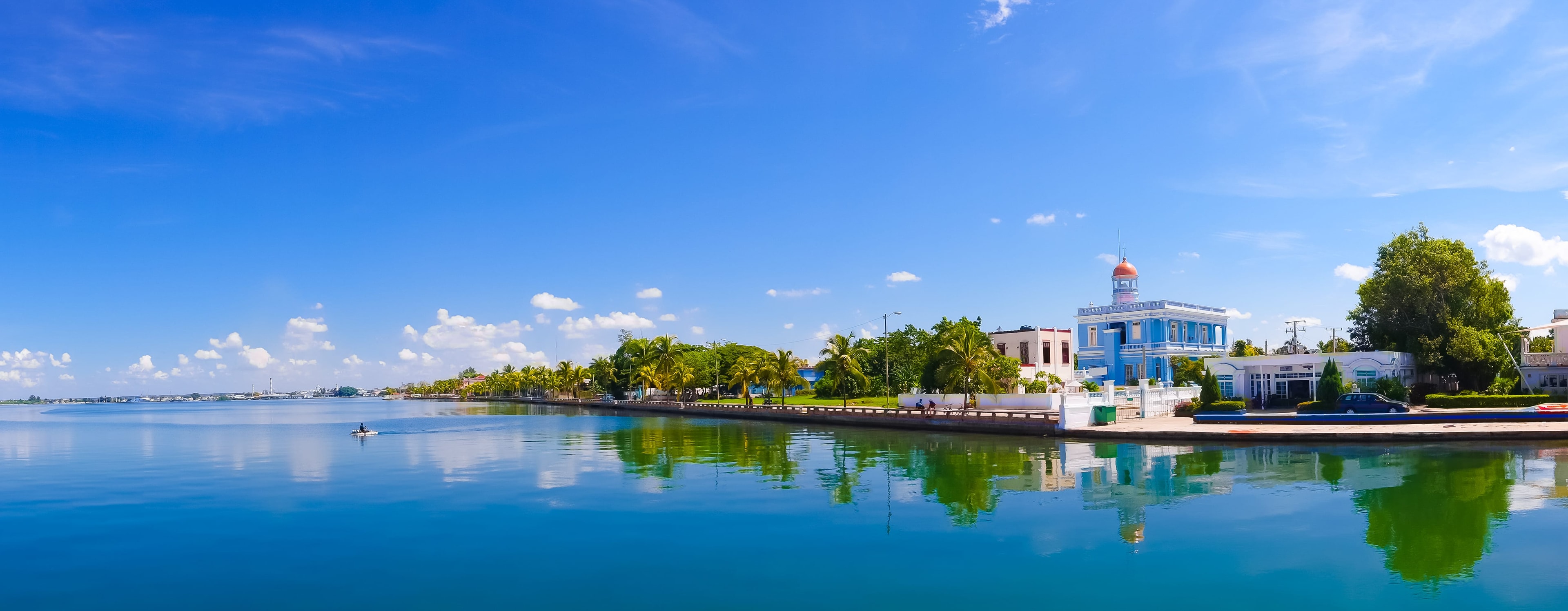 Cienfuegos waterfront promenade with blue colonial building and calm bay reflections Cuba