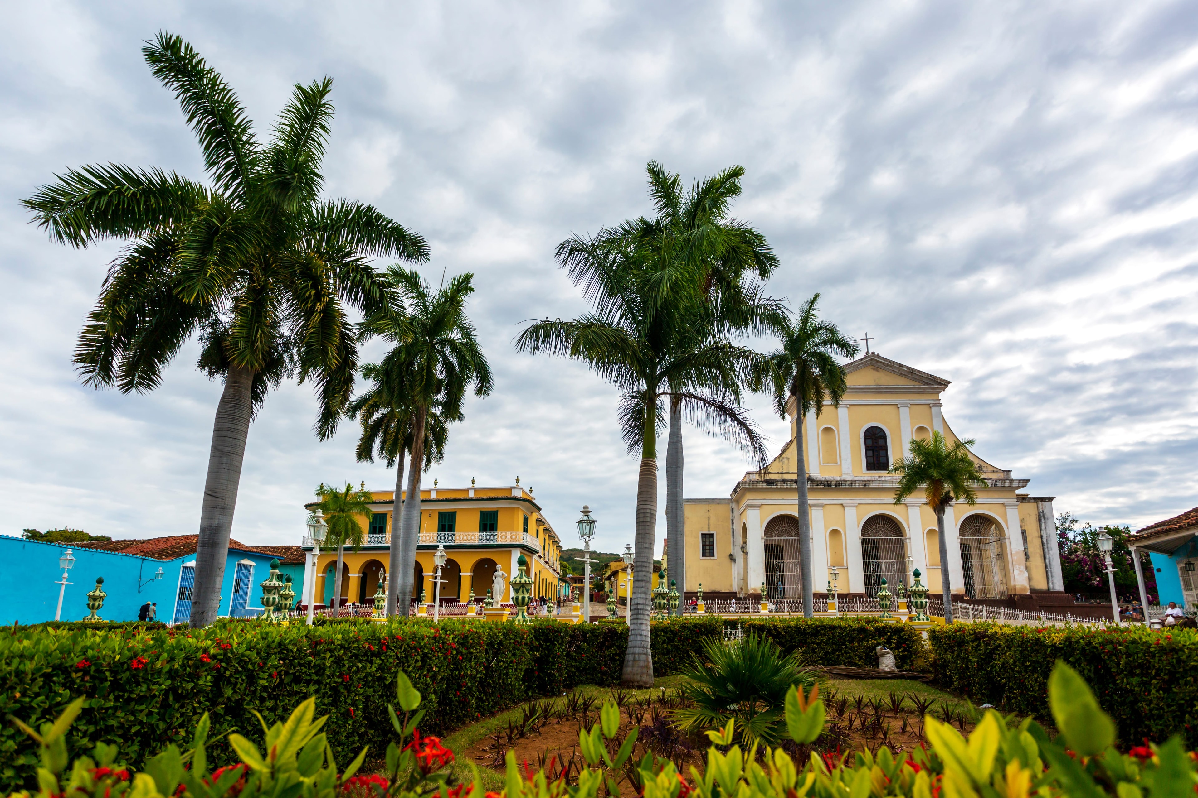 Trinidad Cuba Plaza Mayor with yellow church, royal palms, and colorful colonial buildings