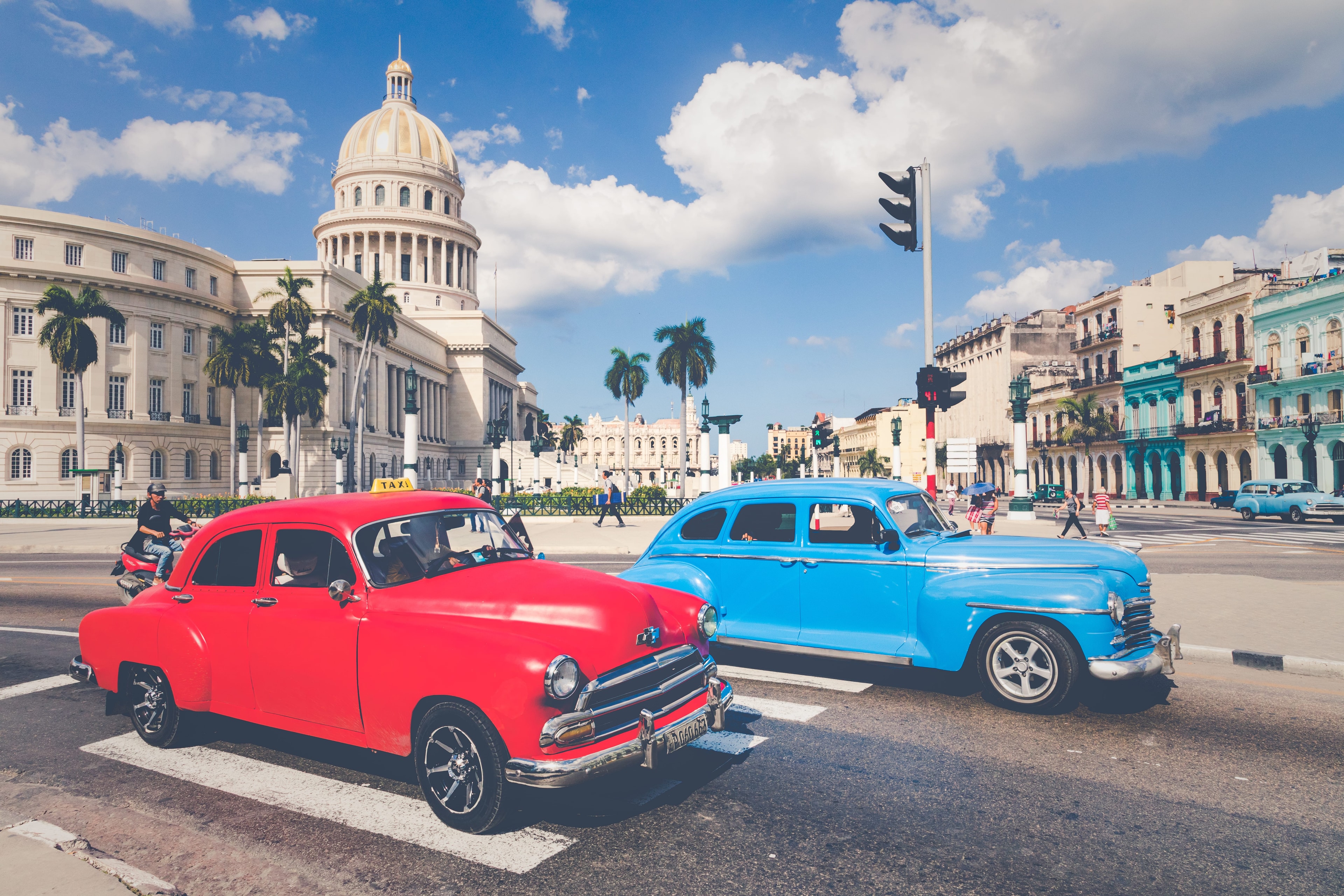Red and blue vintage classic cars at intersection in front of El Capitolio Havana Cuba