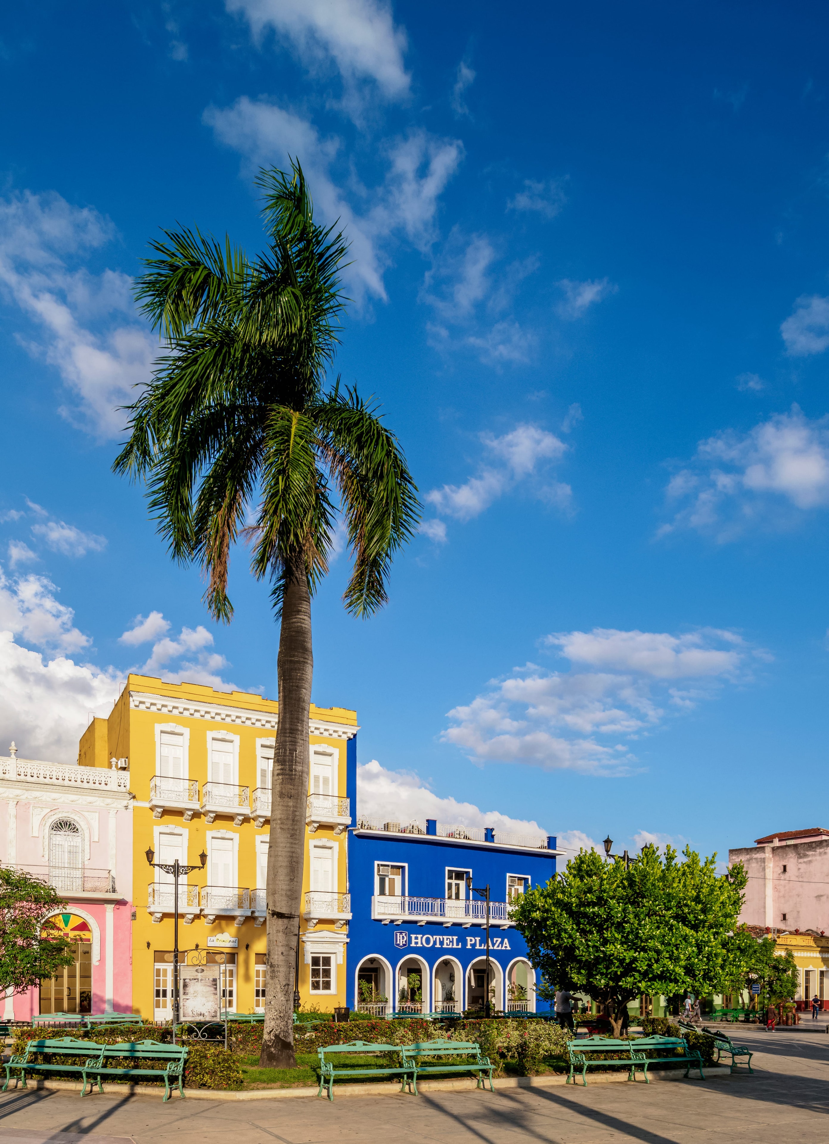 Colorful colonial plaza with royal palm, yellow and blue Hotel Plaza facade, Sancti Spíritus Cuba